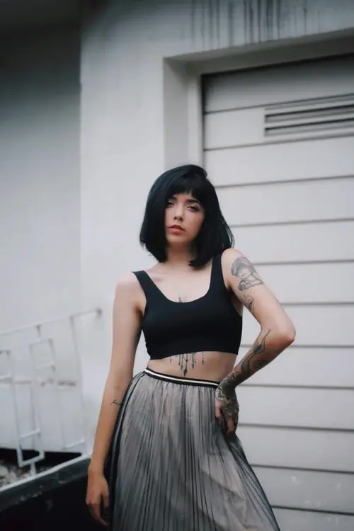 MYSTICA — black top and pleated skirt outdoors